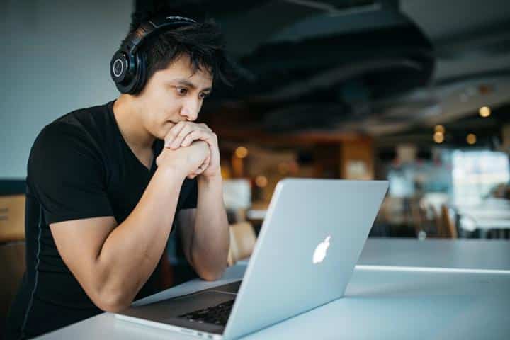 Person sitting at desk with headphones on working on laptop